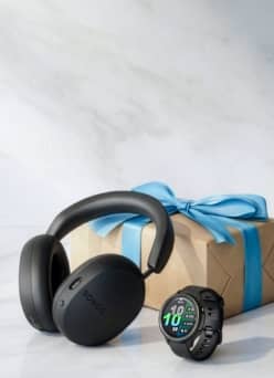 Sonos headphones and Garmin watch in front of wrapped gift box.